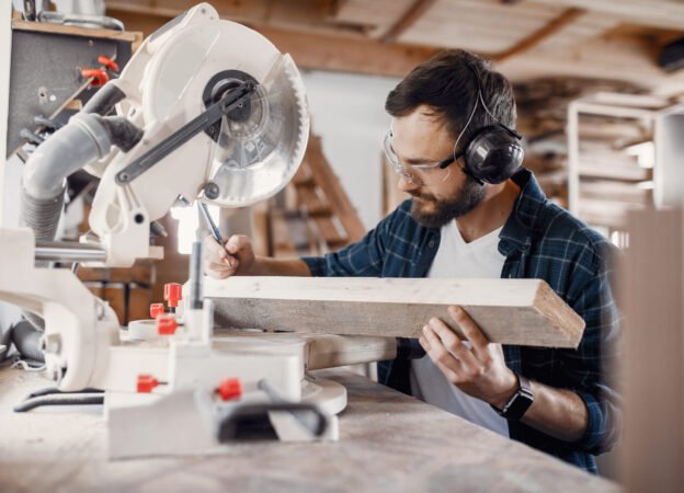 Wood cutting with circular saw. Closeup of mature man sawing lumber.