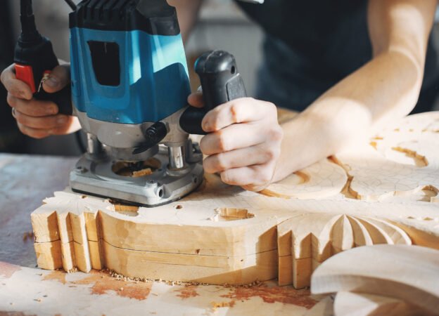 A man carves a tree. The carpenter works in a studio. An engineer provides a tree shape