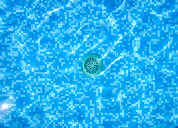 Drain of a pool, seen through the water from above.